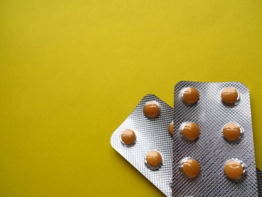 Sarı arka planda bir sürü hap. Hastalıkların tedavisi için kapsüllü haplar, vitaminler ve kabarcıklar. Boşluğu kopyala