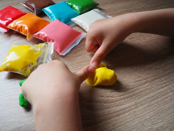プラスチック製のクラス 子供の手は柔らかいプラスチックを粉砕します プラスチックのパッケージがテーブルの上にあります 手の細かいモータースキルの開発のための創造性 プラスチック製 — ストック写真