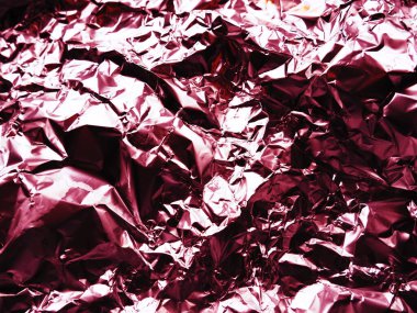 Folyo yakın plan. Alüminyum gümüş buruşuk folyo. Soyut metalik arka plan. Yemek pişirmek için folyo. Kırmızı veya bordo renkli bir arkaplan.