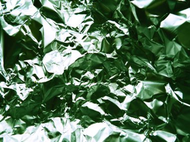 Folyo yakın plan. Alüminyum gümüş buruşuk folyo. Soyut metalik arka plan. Yemek pişirmek için folyo. Yeşil renkli bir arkaplan.