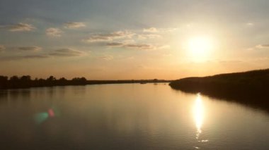 Sırbistan 'ın Sava nehri üzerinde gün batımı, Sremska Mitrovica. Güneş parlıyor. Suyun yüzeyindeki güneşli yol. Altın saat. Ormanlı sahil. Güzel manzara. Balkanlar 'ın doğası