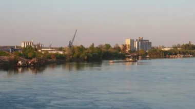 Mavna nehir kıyısından sanayi bölgesiyle ayrılıyor. Sava Nehri, Sırbistan ve Sremska Mitrovica 'da su akışı. Suyun yüzeyinde serinleyin. Binalar, fabrika yapıları, mavnalar, limanlar.