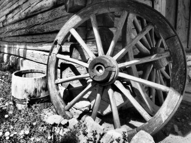 Tahta tekerlek, el arabasından. Dekorasyon için dekoratif tekerlekler, dış mekan ve kır evleri. Yuvarlak ev yapımı tekerlek duvara karşı Retro veya klasik tarzda. Kırsalda hayat siyah beyaz