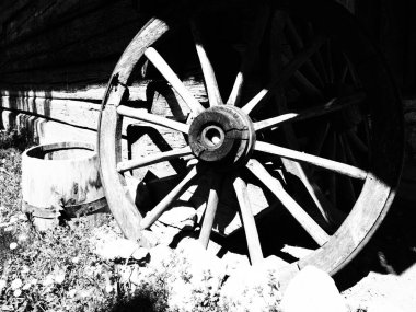Tahta tekerlek, el arabasından. Dekorasyon için dekoratif tekerlekler, dış mekan ve kır evleri. Yuvarlak ev yapımı tekerlek duvara karşı Retro veya klasik tarzda. Kırsal kesimde hayat. Siyah ve beyaz.