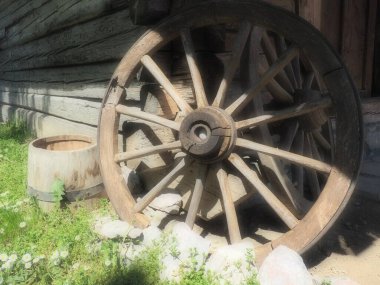 Tahta tekerlek, el arabasından. Dekorasyon için dekoratif tekerlekler, dış mekan ve kır evleri. Duvara karşı yuvarlak ev yapımı tekerlek. Retro ya da eski tarz. Kırsal kesimde hayat.