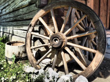 Tahta tekerlek, el arabasından. Dekorasyon için dekoratif tekerlekler, dış mekan ve kır evleri. Duvara karşı yuvarlak ev yapımı tekerlek. Retro ya da eski tarz. Kırsal kesimde hayat.