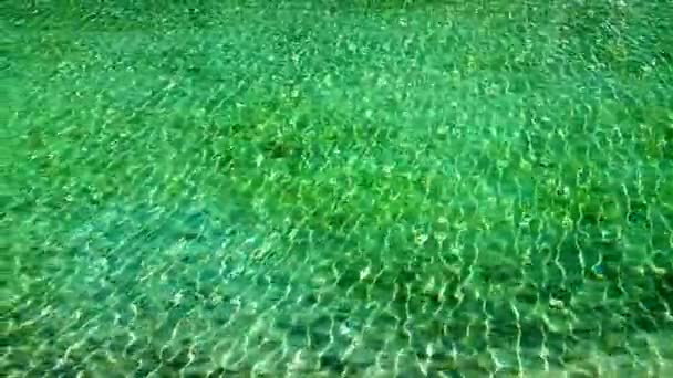 Acqua di mare turchese infusa di raggi solari. Ondate nell'acqua dal vento. Acqua limpida blu. Onde e fondo sabbioso traslucido. — Video Stock