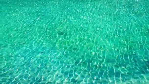 ターコイズブルーの海の水に太陽光線が注入された。風から水の中に波紋。青い澄んだ水。波と半透明の砂底. — ストック動画