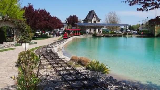 Stanisici, Bijelina, Bosnie-Herzégovine, 25 avril 2021. Une locomotive à vapeur pour enfants avec des personnes et des enfants conduit les passagers. La locomotive et les wagons sont peints en rouge. Parc d'attractions d'été. Jouet ferroviaire — Video