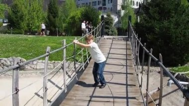 Askıya alınmış ahşap köprü. Çocuk köprüyü sallamaya çalışıyor. Stanisici, Bijelina, Bosna-Hersek. Tahta ve parmaklıklardan yapılmış bir köprü, 4 kişi tarafından taşınabilir..