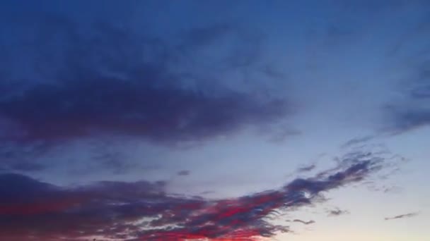 Tijdsverloop van bewolkte lucht met paarse pluizige cumulus wolken zweven snel door de wind bij blauwe lucht, terwijl zonsondergang. Dramatische wolkenkrabber bij zonsondergang — Stockvideo