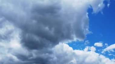 Mavi gökyüzünde beyaz ve koyu bulutlar hızla uçar. Zaman atlamalı atmosfer. Hava değişiyor. Gökyüzünde bulutların hareketi. Gökyüzü arkaplanı