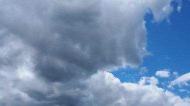 Mavi gökyüzünde beyaz ve koyu bulutlar hızla uçar. Zaman atlamalı atmosfer. Hava değişiyor. Gökyüzünde bulutların hareketi. Gökyüzü arkaplanı