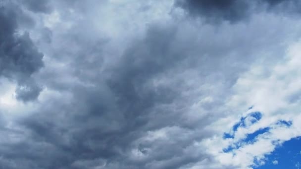 白い雲と暗い雲が青空を横切って急速に飛ぶ。時間の経過の雰囲気。天候の変化。空を渡る雲の動き。空の背景 — ストック動画