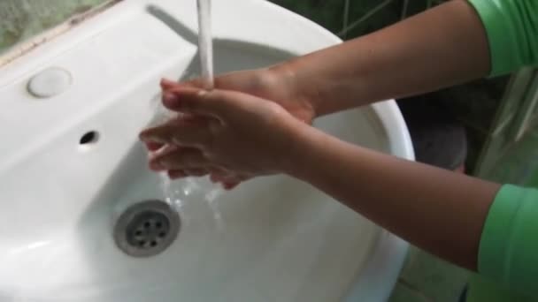 Ein 7-jähriges Mädchen wäscht sich die Hände über dem Waschbecken. Kinderhände unter einem Strom sauberen Wassers, das aus dem Wasserhahn fließt. Hygiene und Prävention von Infektionskrankheiten. Badezimmer oder öffentliche Toilette — Stockvideo