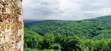 Ruins of an old fortress in Vrdnik, Sremska Mitrovica, Vojvodina, Serbia. Ancient stone walls with mountain ranges in the background. Tourist historical sights. Edge of the wall. clipart