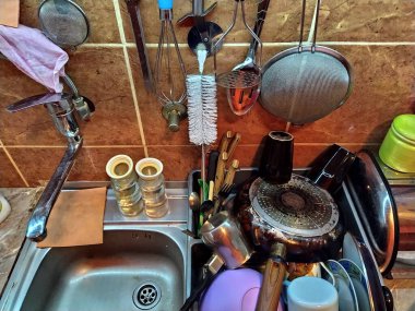 Belgrade, Serbia, December 12, 2020 Kitchen, countertop with sink, top view. Home daily life. The washed dishes are stacked near the sink. Kitchenware is hung on the tile wall. Colander, sponges rags.