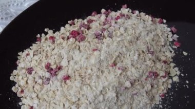 Organic Granola Cereal with oats, powdered sugar and dry raspberries. Healthy muesli as a dry mix. An antidiabetic, low calorie, healthy diet. Black utensils.
