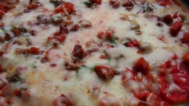 Pizza entière à proximité. Délicieuse pizza ronde juteuse aux tomates, salami. Le fromage fondu se déverse sur la surface du gâteau cuit au four. Vue supérieure et latérale de la pizza. — Video