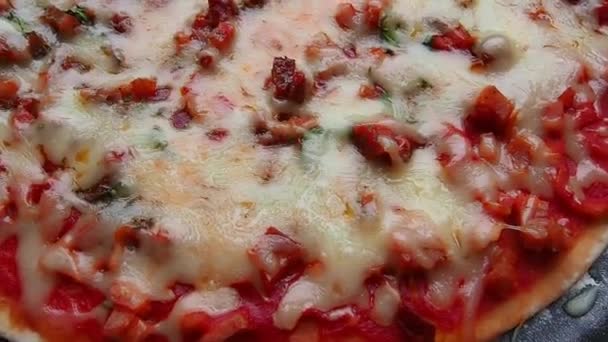 Pizza entière à proximité. Délicieuse pizza ronde juteuse aux tomates, salami. Le fromage fondu se déverse sur la surface du gâteau cuit au four. Vue supérieure et latérale de la pizza. — Video