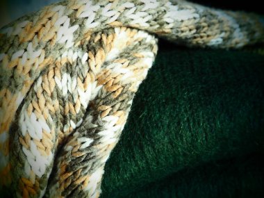Örgü kıyafetler, gelişigüzel katlanmış. Dalgalı polyester ve yeşil yün kazaklar. Sıcak kışlık giysiler. Örgü tarzı sakız. Yüksek kalite fotoğraf.