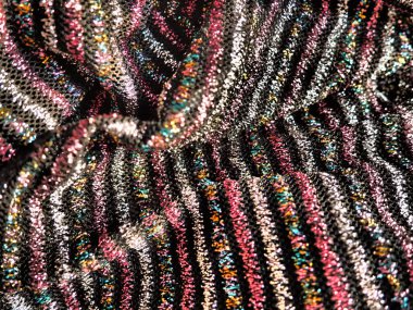 Kumaşlı kumaş. Siyah arka planda pembe, kırmızı, gümüş ve altın çizgileri olan çizgili zarif kumaşlar. Yanan kumaş, dikkatsizce katlanmış dalgalarla.