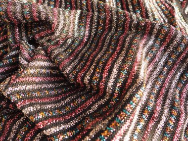 Kumaşlı kumaş. Siyah arka planda pembe, kırmızı, gümüş ve altın çizgileri olan çizgili zarif kumaşlar. Yanan kumaş, dikkatsizce katlanmış dalgalarla.