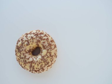Mavi arka planda donut yakın plan. Vanilya kreması ve çikolata parçacıklarıyla kaplı lezzetli bir pasta. Yüksek kalorili kahvaltı ya da atıştırmalık. Vanilyalı, çikolatalı, çörekli ya da hamurlu lezzetli bir tatlı..