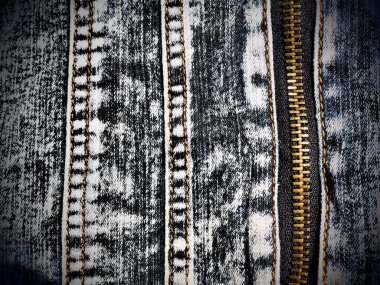 Dikişleri ve kilitleri olan yakın plan kot pantolon. Ağır, pejmürde bir kot pantolon. Metal bronz kilit ve koşucu. Dikey dikişler.