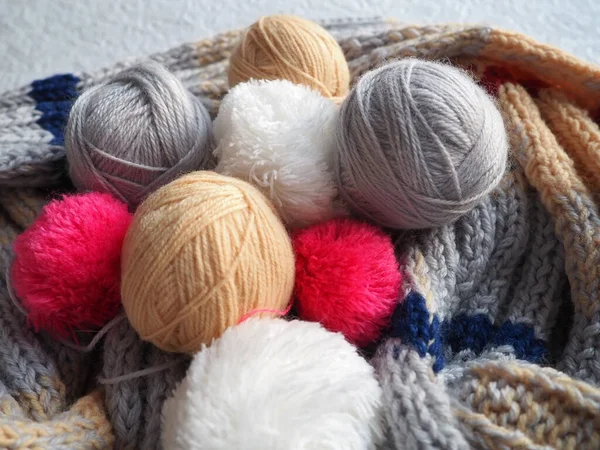 Tangles of yarn, threads, warm scarf on a white-gray background. Knitting as a hobby. White, beige, grey, red subester and wool yarn.