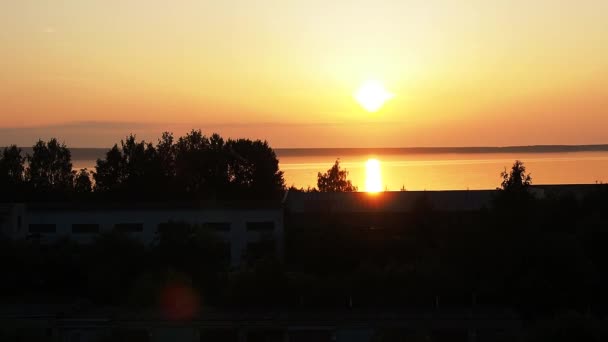 Alba giallo-arancio e la salita del sole sul lago Onega in estate. Alba e sollevamento del disco solare dalle nuvole. Riflessione del sole nell'acqua. Traccia solare sulla superficie dell'acqua — Video Stock