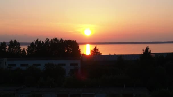Amanecer amarillo-anaranjado y el ascenso del sol sobre el lago Onega en verano. Amanecer y levantar el disco solar de las nubes. Reflejo del sol en el agua. Pista solar en la superficie del agua — Vídeo de stock