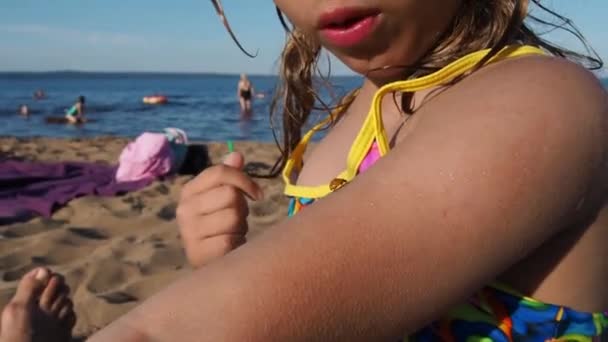 Petrozavodsk, Rusia, 10 de julio de 2021. Una chica en una playa de arena. Un escarabajo mariquita se arrastra en la mano del niño. La chica protege al escarabajo. Insectos en la playa. Ayuda para los animales. Verano playa diversión. — Vídeo de stock