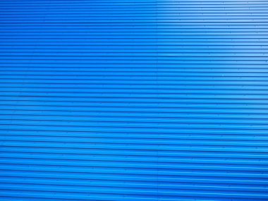 Profiled sheet. Facing wall or roofing building material used in construction in the construction of external fences, walls and roofs. Corrugated blue metal background with gradient.