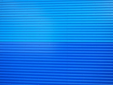 Profiled sheet. Facing wall or roofing building material used in construction in the construction of external fences, walls and roofs. Corrugated blue metal background with gradient.
