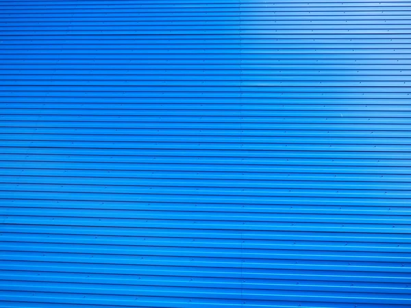 Profiled sheet. Facing wall or roofing building material used in construction in the construction of external fences, walls and roofs. Corrugated blue metal background with gradient.