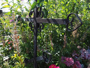 Mezarda metal haç. Mezarlıkta haç şeklinde bir anıt. Yazın gündüz. Keder, ölüm ve Cadılar Bayramı teması. Ruhun dinginliğinin dini Hristiyan sembolü.