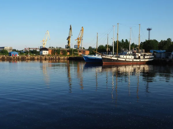 Petrozavodsk, Russie, 10 juillet 2021. Port avec grues à cargaison et navires. Yachts et bateaux de plaisance en bois. Bâtiments industriels. Lac d'Onega, Carélie. Marine, transport et thème touristique. Le soir. — Photo