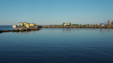 Petrozavodsk, Rusya, 10 Temmuz 2021 Nehir İstasyonu veya limanı. Depolar ve üretim tesisleri. Onega Gölü 'ndeki iskele, Karelia. Araba lastikleri rıhtımın kenarlarına yerleştirilir. Su, gökyüzü ve ufuk.
