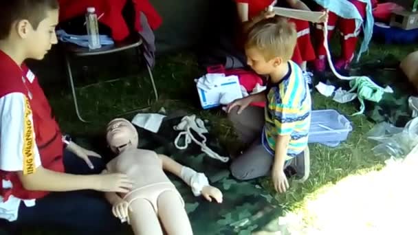 Sremska Mitrovica, Serbia, 18 de mayo de 2019. Los niños con trajes médicos enseñan al niño a proporcionar primeros auxilios para las lesiones. Medicina de campo y cirugía. Determinación de trauma y diagnóstico en el modelo — Vídeos de Stock