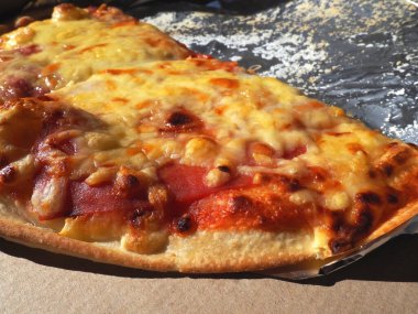 Domatesli pizza, karton kutuda peynir ve alüminyum folyo. Lezzetli pizza, yakından. Evinize kurye teslimatı. Pizza sipariş ediyorum. Geleneksel İtalyan hamur tatlısı..