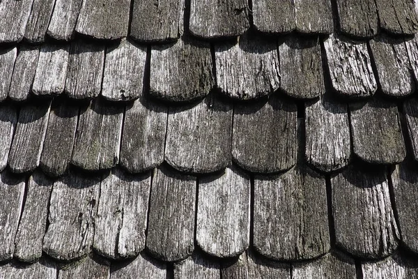 Roof shingles as a traditional rural roof covering. Tiled acute angled cross slab roofing piece material close-up. Wooden architecture of ancient craftsmen - carpenters. Natural background