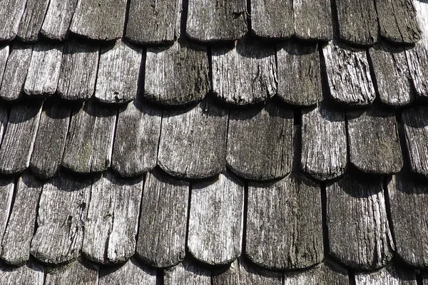Roof shingles as a traditional rural roof covering. Tiled acute angled cross slab roofing piece material close-up. Wooden architecture of ancient craftsmen - carpenters. Natural background