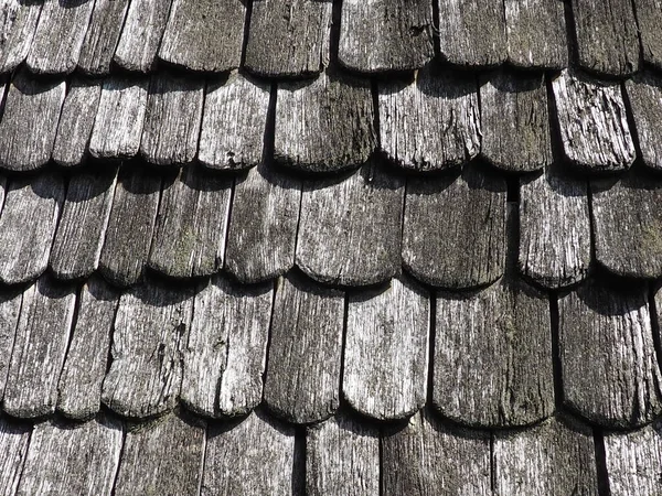 Roof shingles as a traditional rural roof covering. Tiled acute angled cross slab roofing piece material close-up. Wooden architecture of ancient craftsmen - carpenters. Natural background