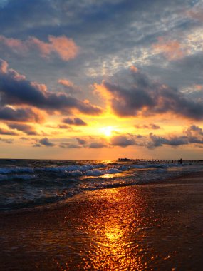 Denizde gün batımı. Güzel gün batımı. Köpüklü dalgalar kumlu sahilde yuvarlanıyor. Vityazevo, Anapa, Karadeniz. Turist Mekke, sağlık merkezi. Akşam gökyüzünde renkli bulutlar. Işınlar sudan yansıyor.