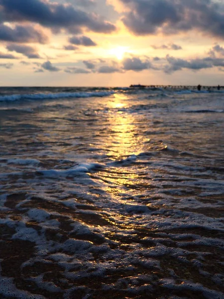 夕阳西下美丽的日落浪花在沙滩上翻滚.Vityazevo，Anapa，黑海。旅游胜地梅卡，健康胜地。夜空中的彩云.光线反射出水面 — 图库照片