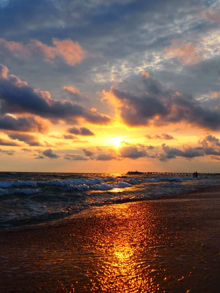 夕阳西下美丽的日落浪花在沙滩上翻滚.Vityazevo，Anapa，黑海。旅游胜地梅卡，健康胜地。夜空中的彩云.光线反射出水面 — 图库照片