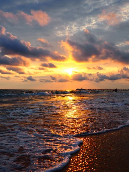 夕阳西下美丽的日落浪花在沙滩上翻滚.Vityazevo，Anapa，黑海。旅游胜地梅卡，健康胜地。夜空中的彩云.光线反射出水面 — 图库照片