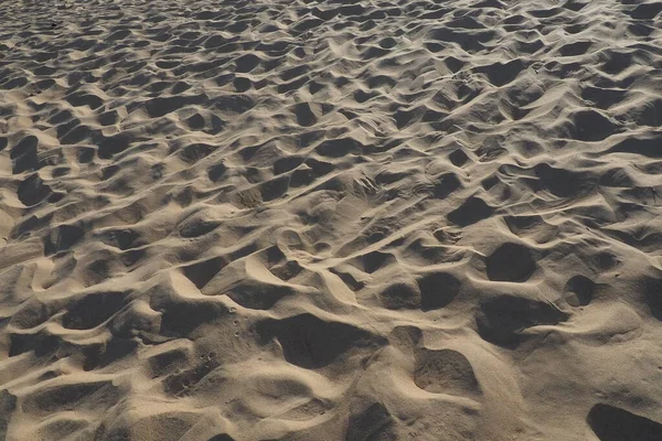 Песок при низком солнечном свете в золотой час. Пустой пляж, следы и вмятины на песке. Дюны Черного моря. Свободные осадочные породы, состоящие из зерен горного и минерального кварцевого диоксида кремния — стоковое фото