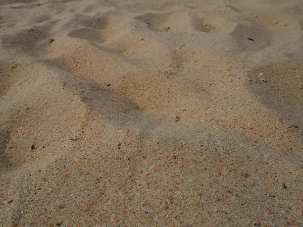 Piasek w słabym słońcu o złotej godzinie. Pusta plaża, ślady stóp i wgniecenia na piasku. Wydmy Morza Czarnego. Luźna skała osadowa składająca się z ziaren górskiego i mineralnego ditlenku krzemu kwarcowego — Zdjęcie stockowe